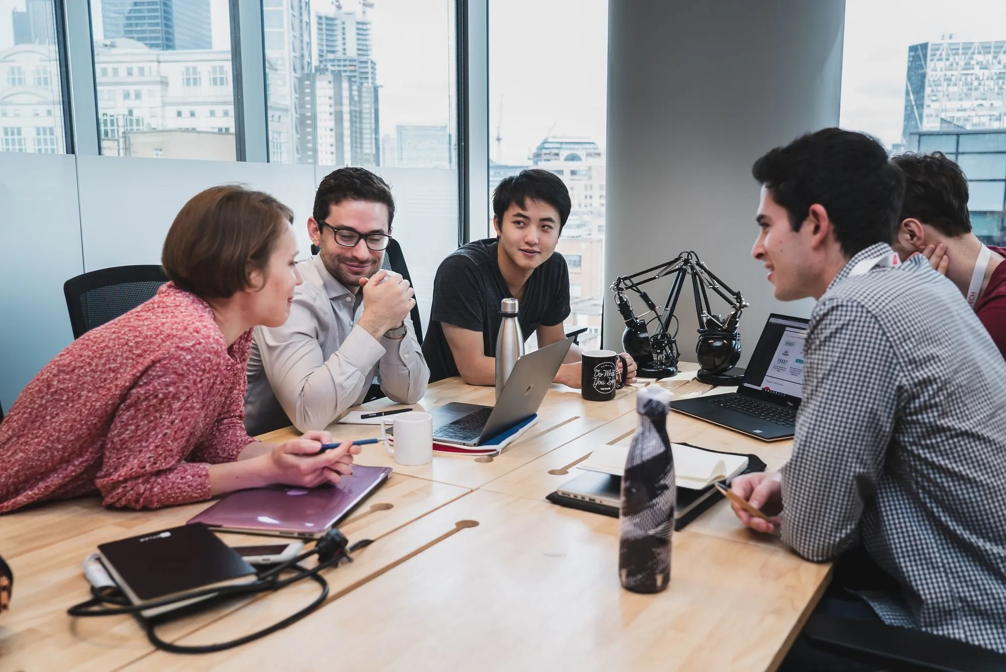 Founders talking around a table in a high-rise office with the city behind them