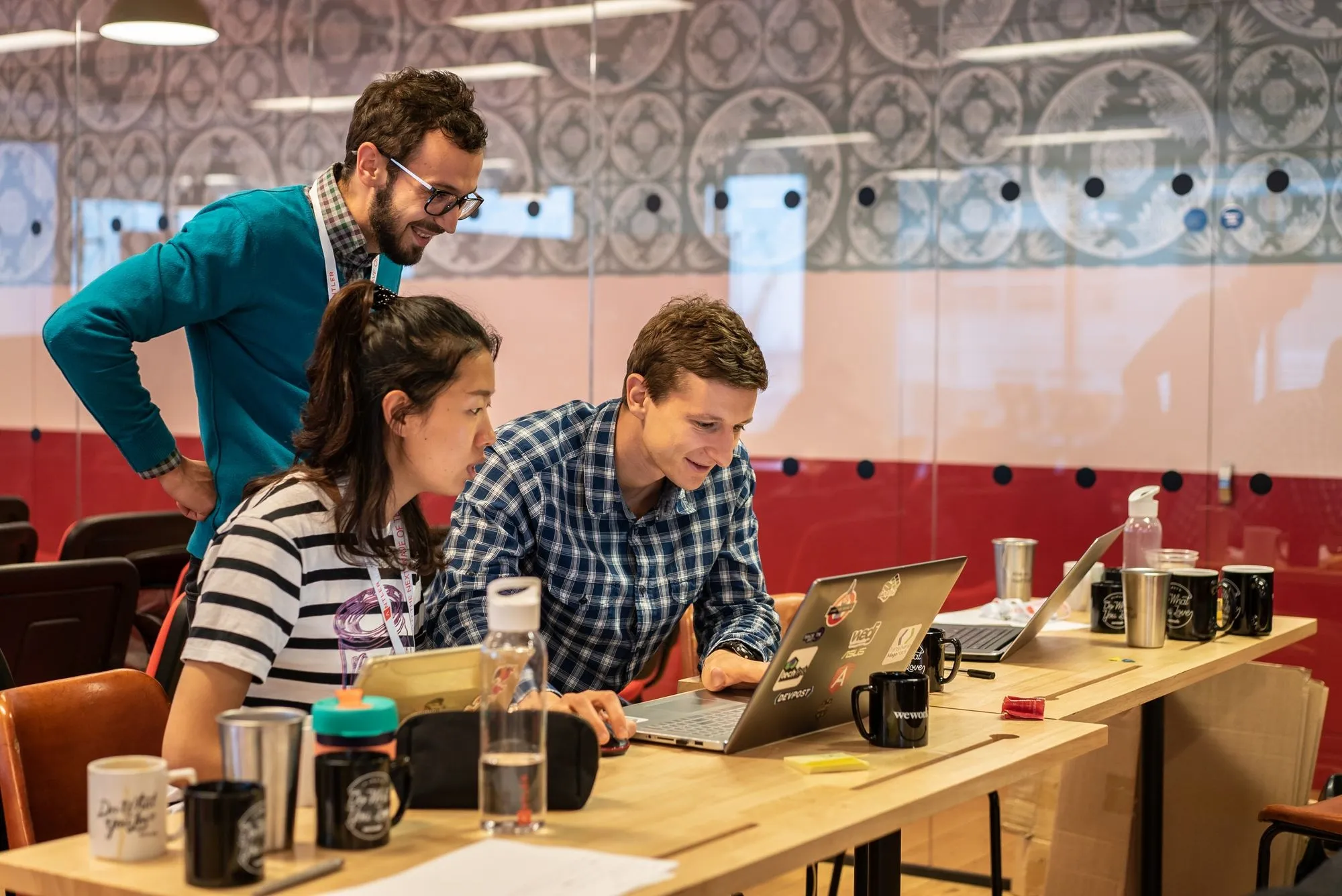 Two founders at a laptop with a mentor looking on